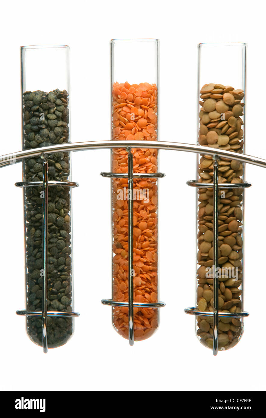 Puy lentils, split red lentils, and brown lentils in glass test tubes in a chrome stand Stock Photo