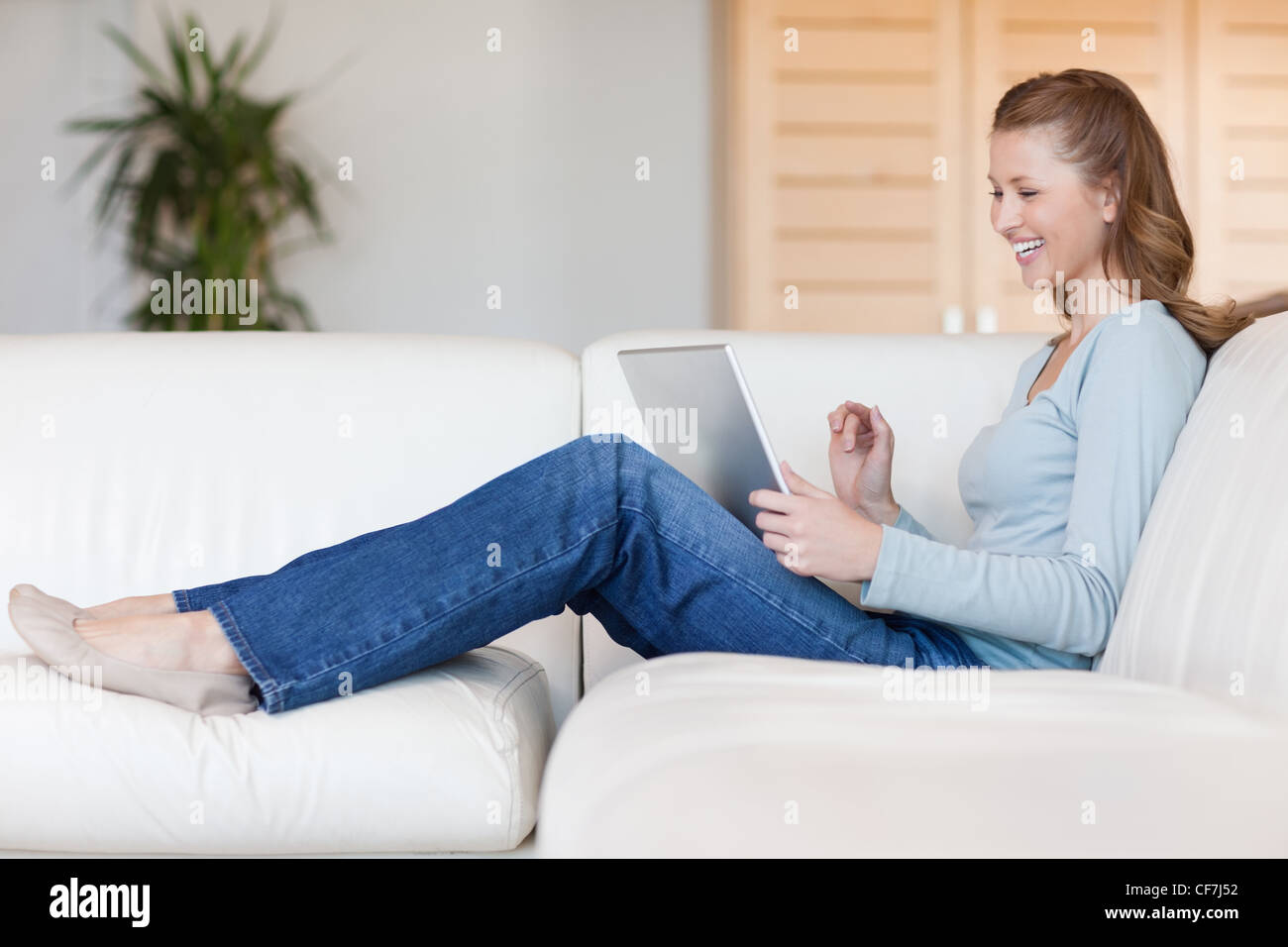 Laughing woman with her laptop on the sofa Stock Photo - Alamy