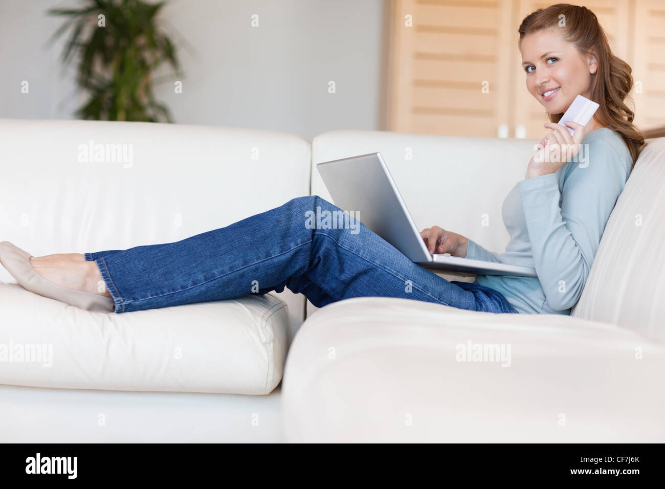 Young woman on the sofa booking a flight online Stock Photo