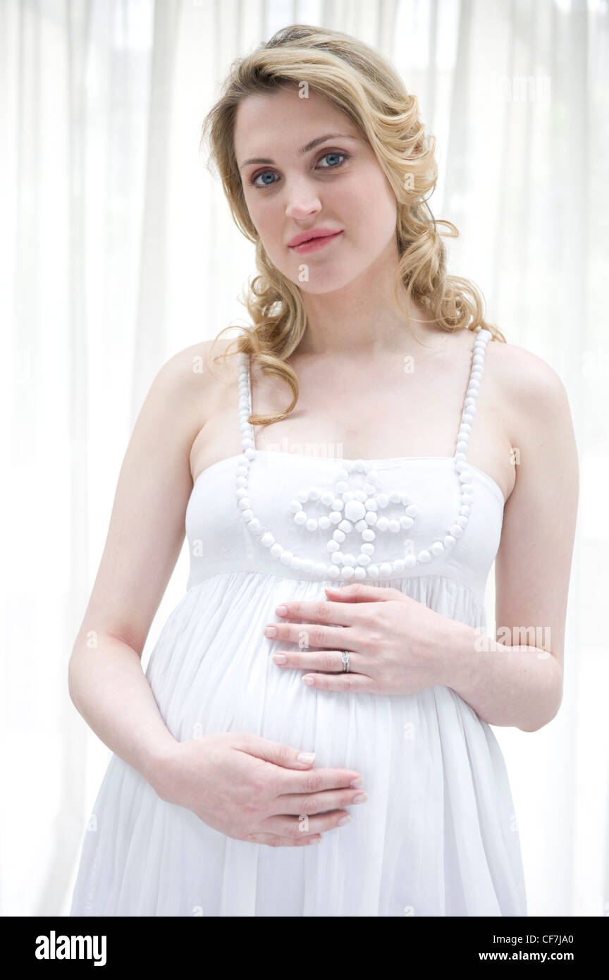 Pregnant Female Wavy Blonde Hair Wearing A White Dress Standing By Stock Photo Alamy