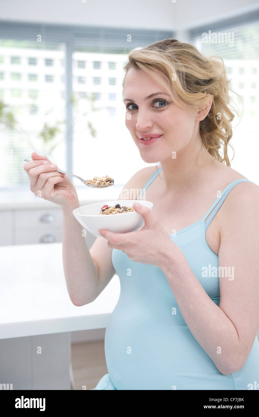 Pregnant female fair hair tied at the back, wearing a blue vest