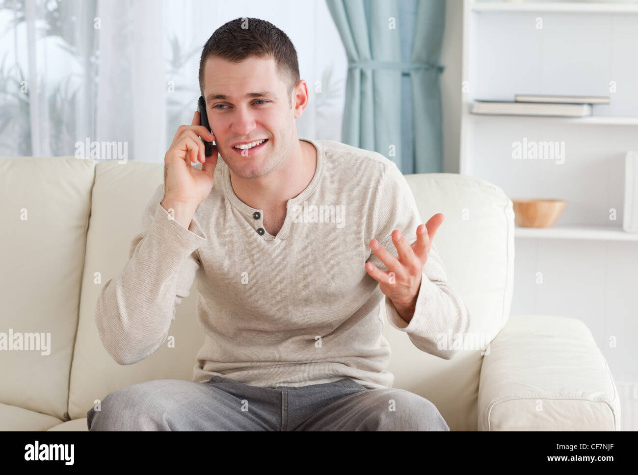 Ничем в телефоне сижу. Человек сидит на диване с телефоном. Мужчина с телефоном дома. Мужчина разговаривает по телефону. Молодой человек с телефоном.