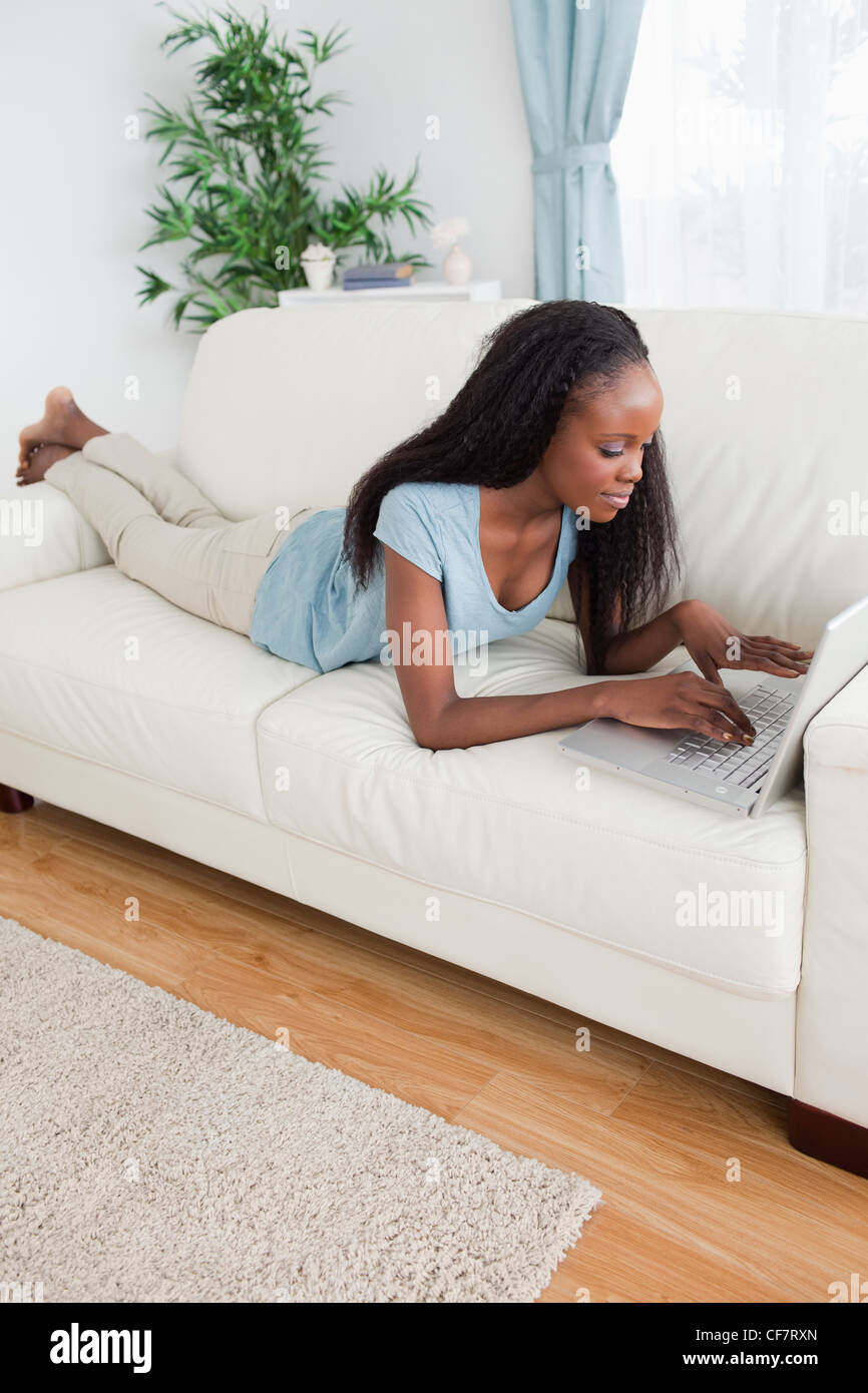 Woman lying on the sofa using her laptop Stock Photo - Alamy