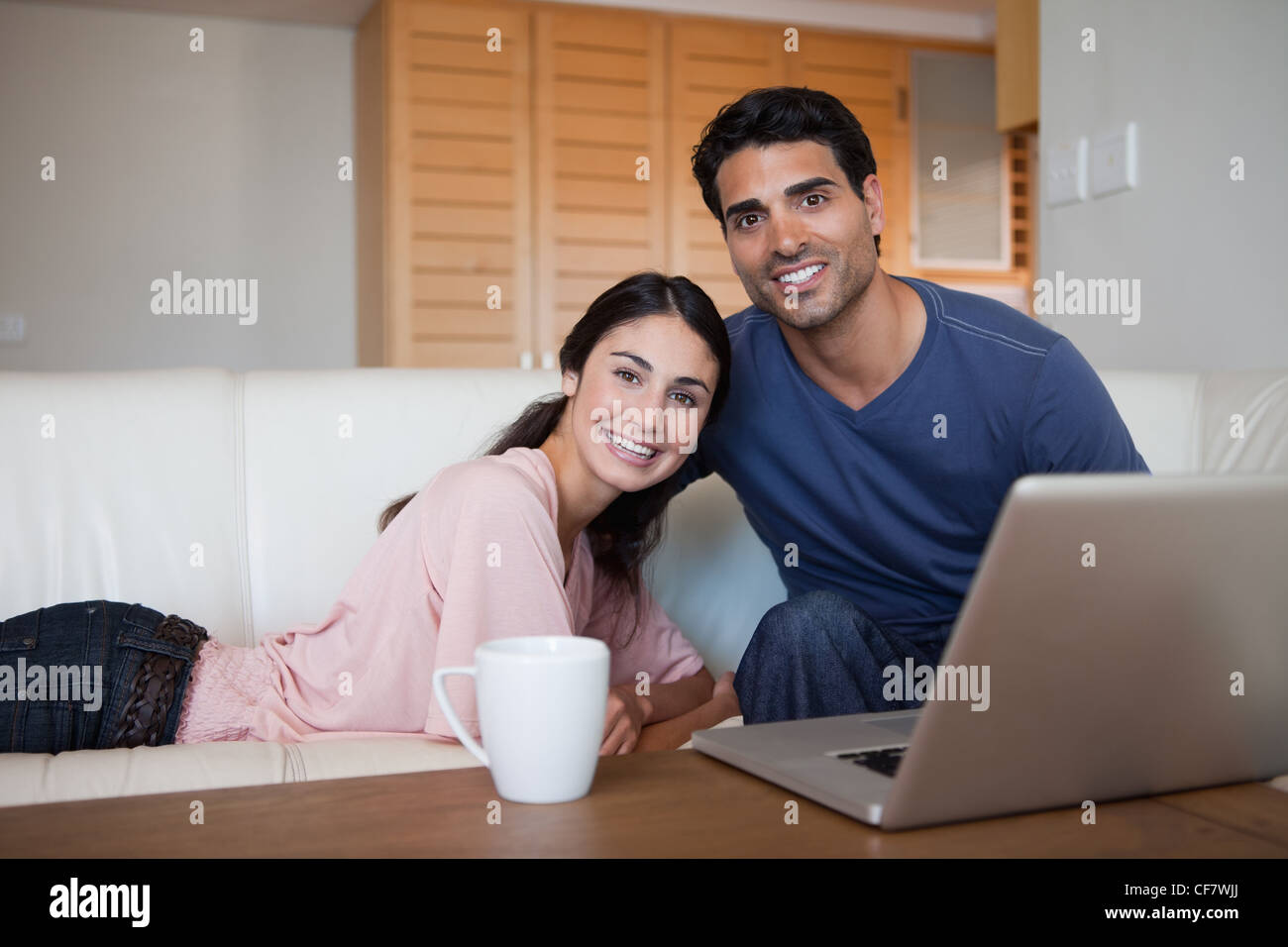 Smiling couple using a laptop while having a tea Stock Photo - Alamy