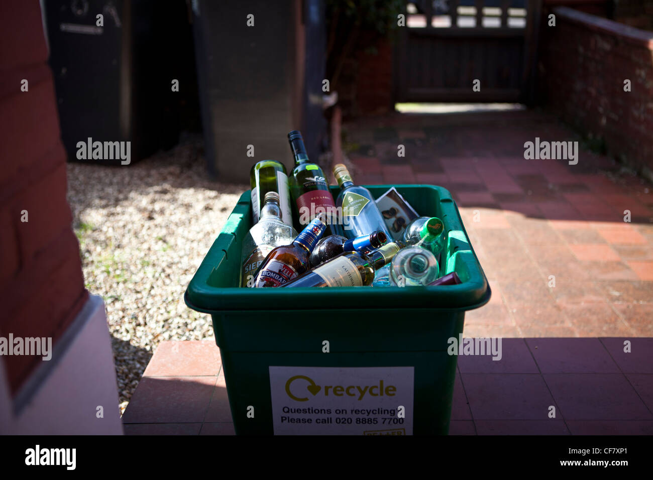 Empty wine, spirit and beer bottles in green recycling bin on doorstep