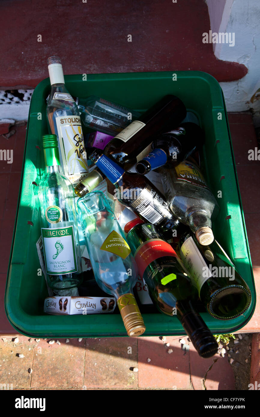 Empty wine, spirit and beer bottles in green recycling bin on doorstep