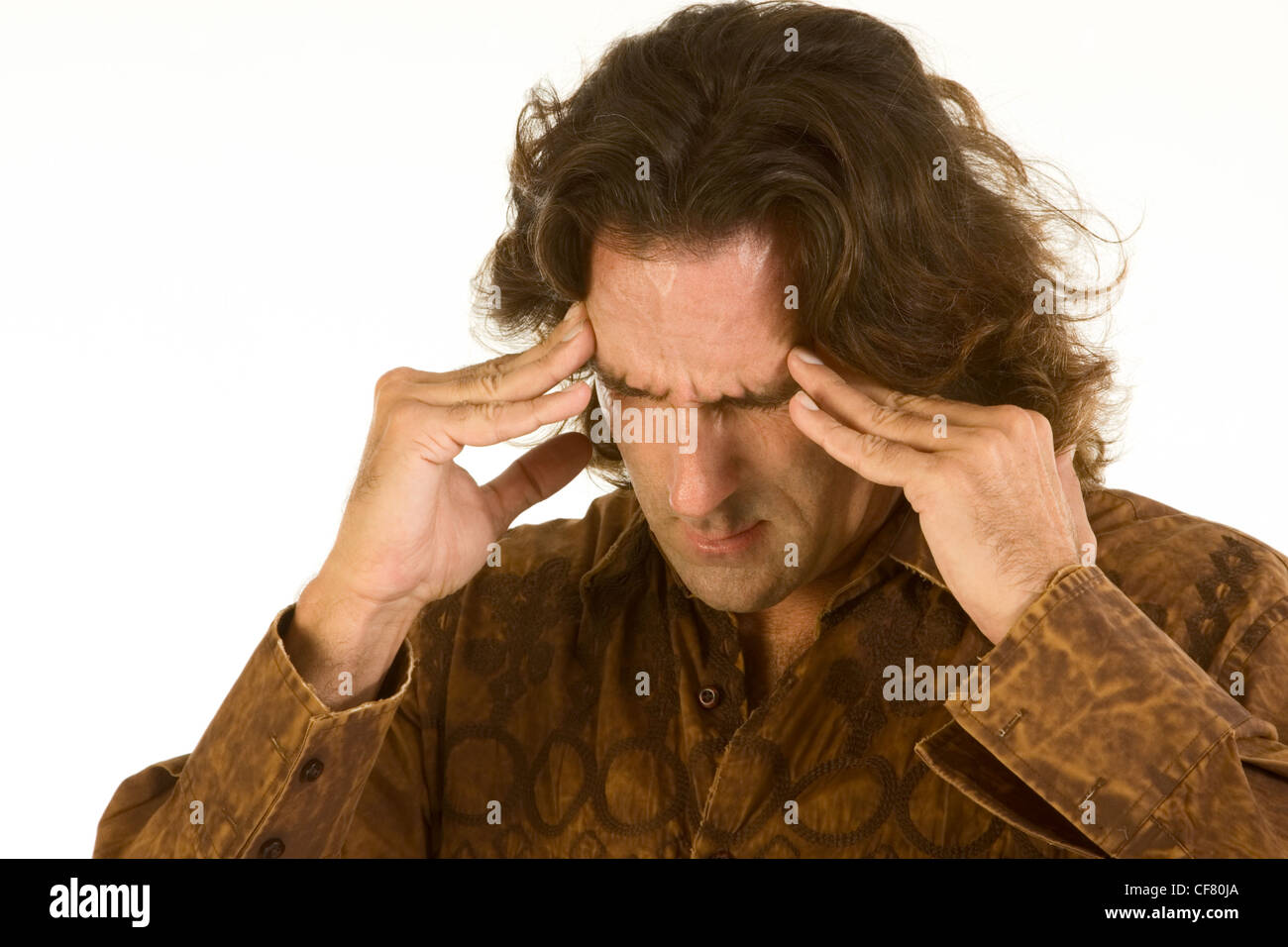 Mid aged man with long hair squeeze his head by hands apparently suffering from headache or extremely stressed out by problems Stock Photo