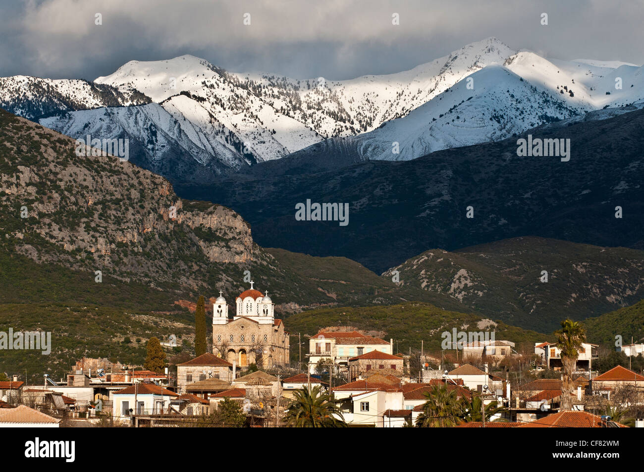 The snow covered mountains of the Taygetos range loom over the Outer Mani village of Kambos, Southern Peloponnese, Greece Stock Photo