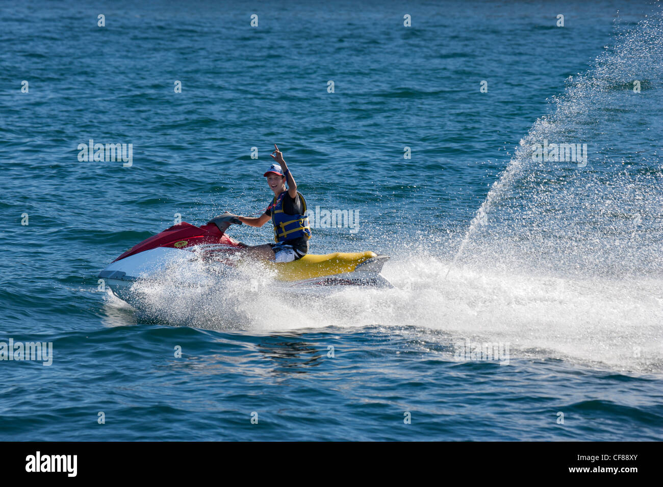 Young man speeding over the Sea of Cortez in the Pacific Ocean in a jetski watercraft near Cabo San Lucas-Mexico. Stock Photo