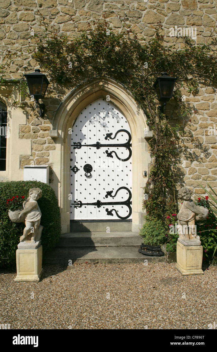 Stone Gothicarched white front door of old rectory with stone statues