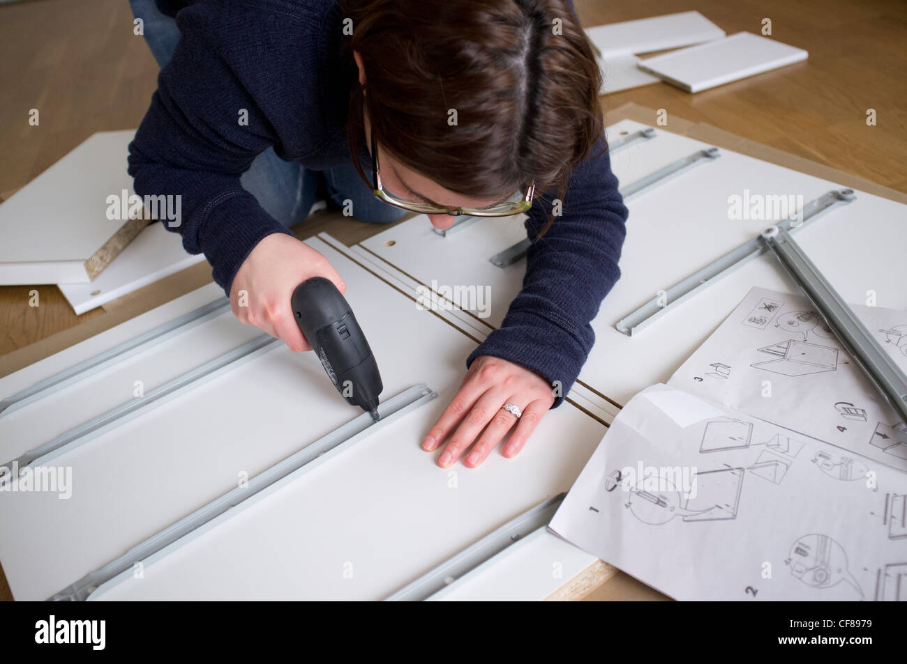 Woman assembling flat-pack furniture from IKEA at home Stock Photo