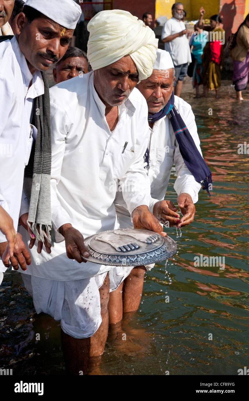 Hindu men making a ritual offering to the sacred river. Godavari river. Nasik. India Stock Photo