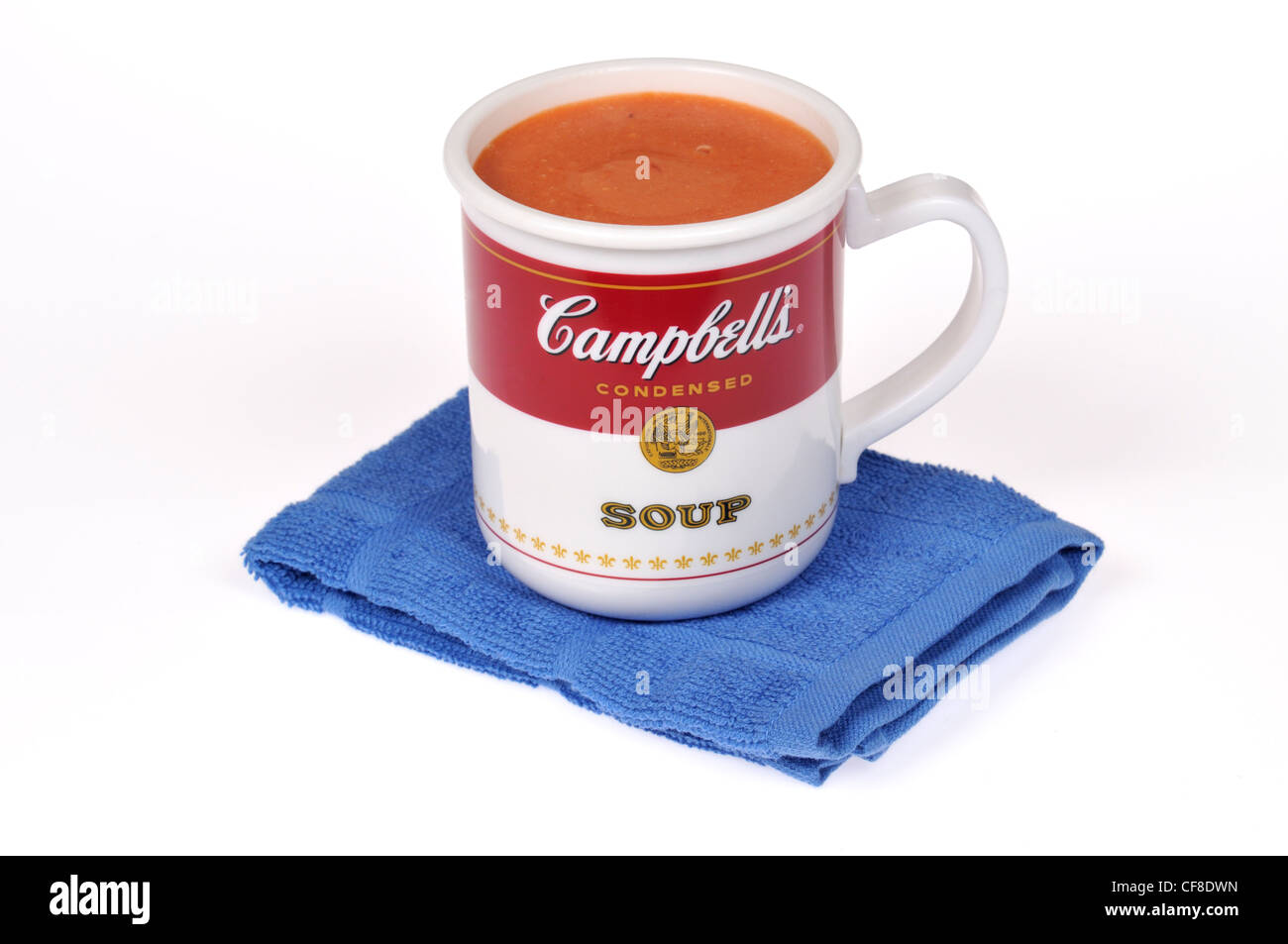 A Campbell's tomato soup in a red and white Campbells cup on blue towel. Stock Photo