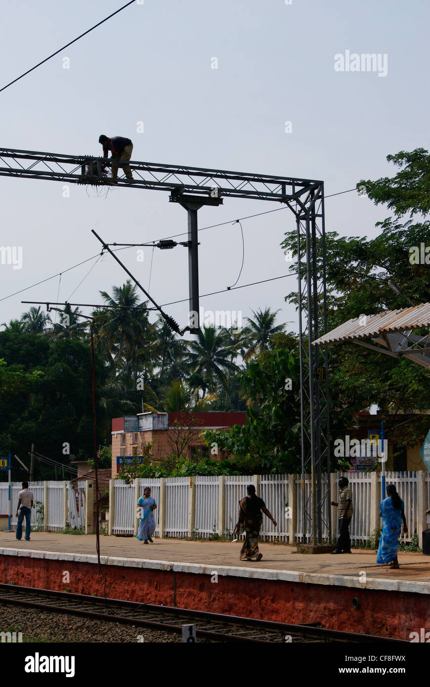 Man taking Birds nest from the top of Heavy Voltage Electric railway line.A Scene from Chirayinkeezhu Railway station ,India Stock Photo