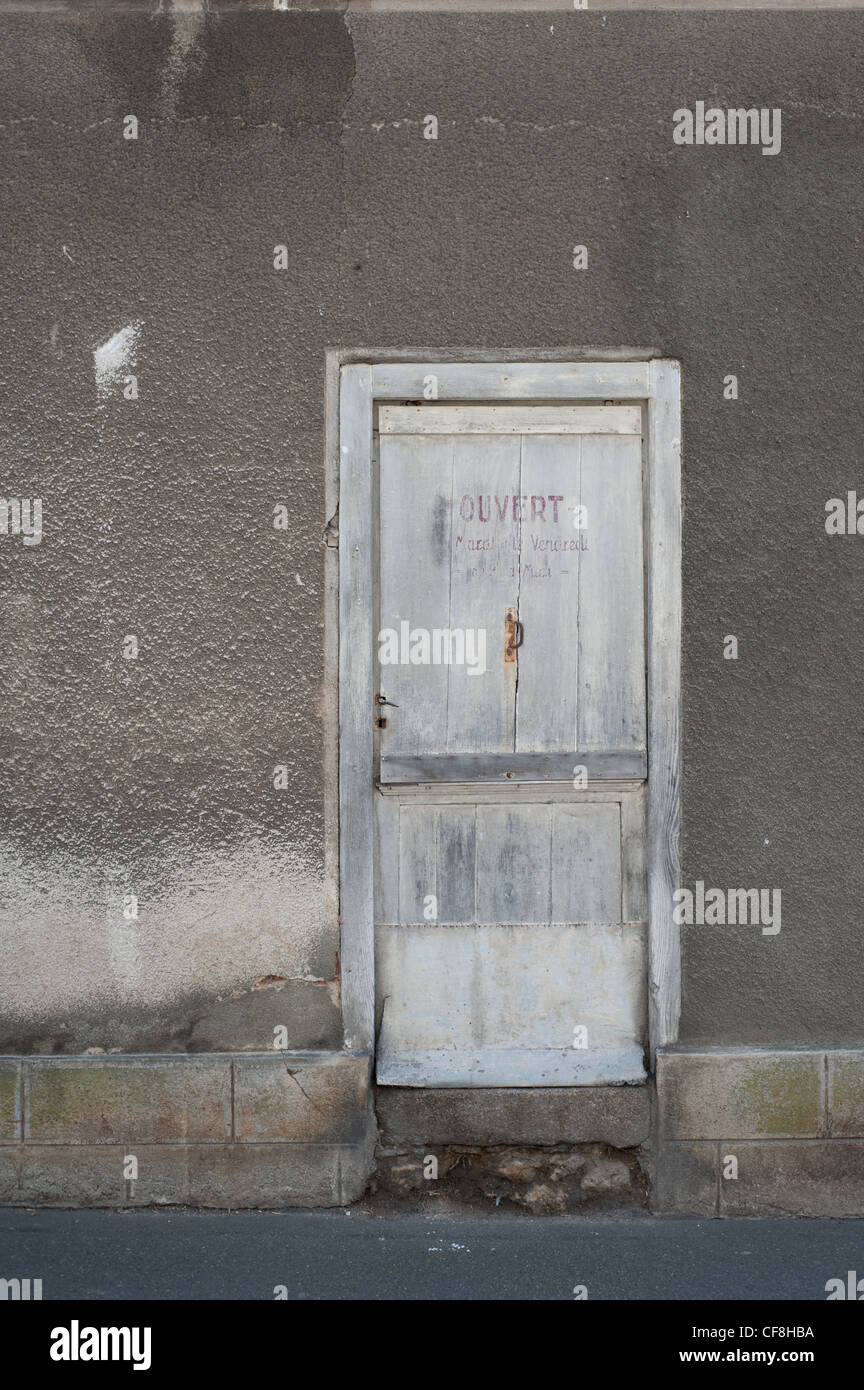 closed door in a wall with the word 'ouvert' (open) in faded paint Stock Photo