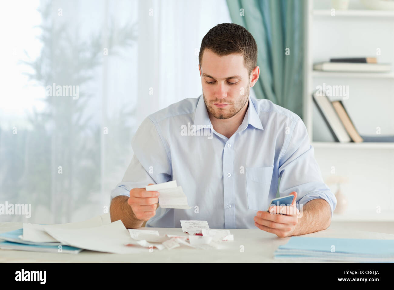 Businessman with pocket calculator checking invoices Stock Photo