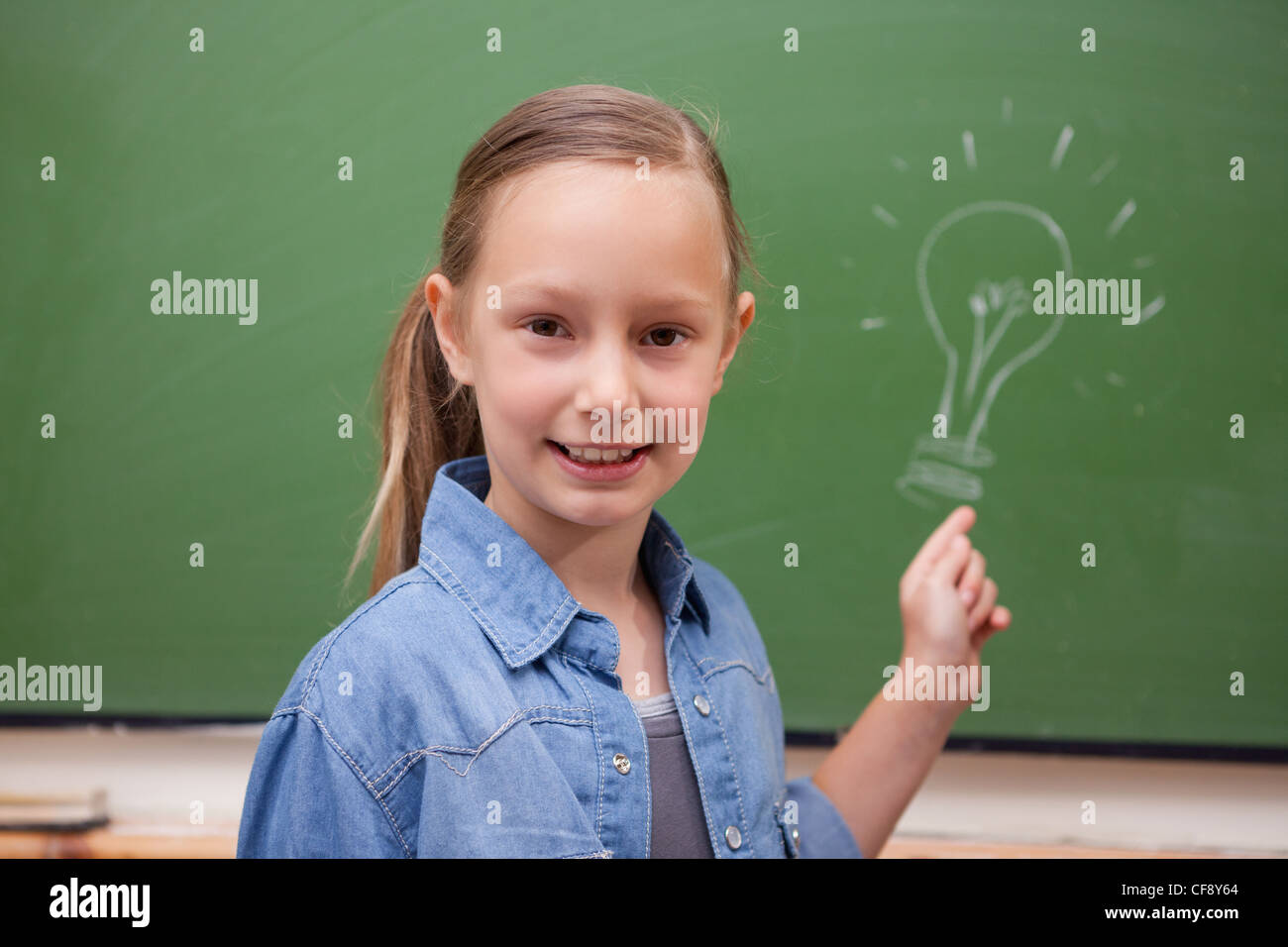 Smiling schoolgirl pointing at a bulb Stock Photo