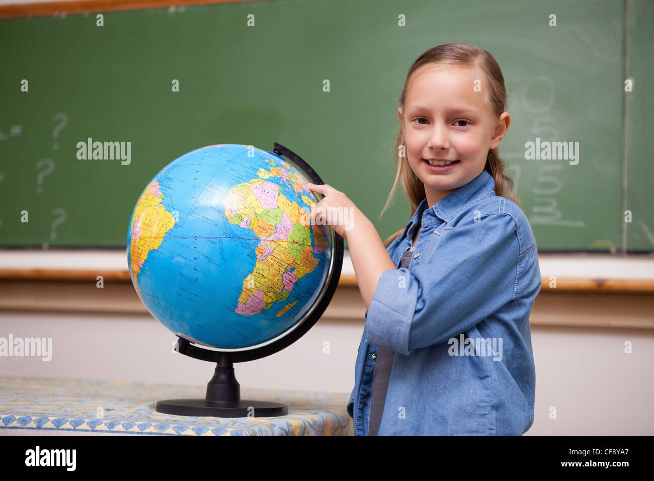 Smiling schoolgirl looking at a globe Stock Photo - Alamy