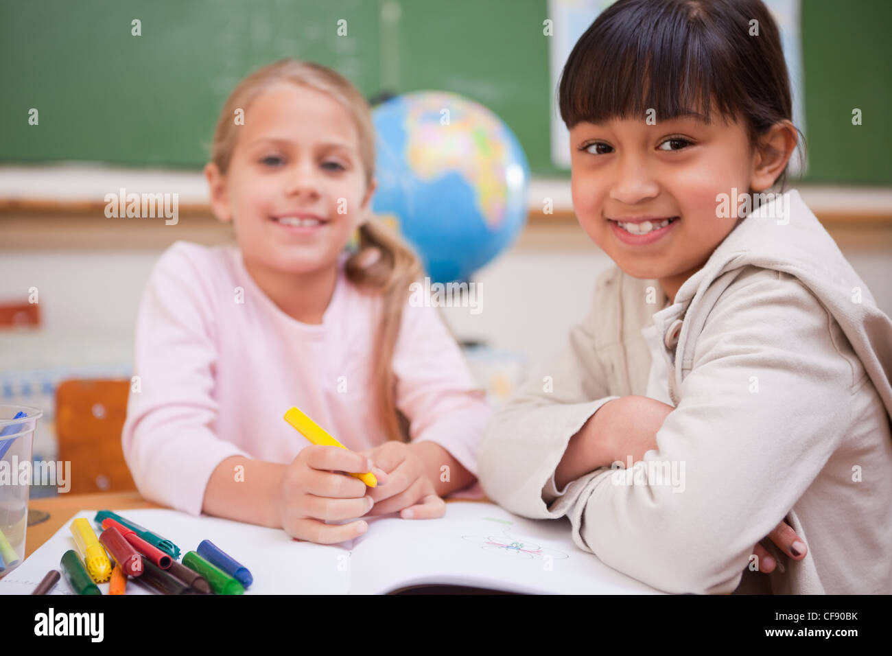 Smiling schoolgirls drawing while looking at the camera Stock Photo - Alamy
