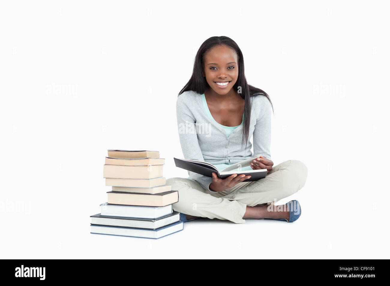 Smiling woman sitting next to a pile of books Stock Photo - Alamy