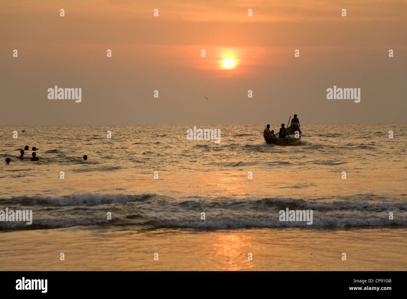 GOA, INDIA - 19 NOV 2011: indian boat and swimming children at sunset in the seaon Arambol beach in Goa Stock Photo