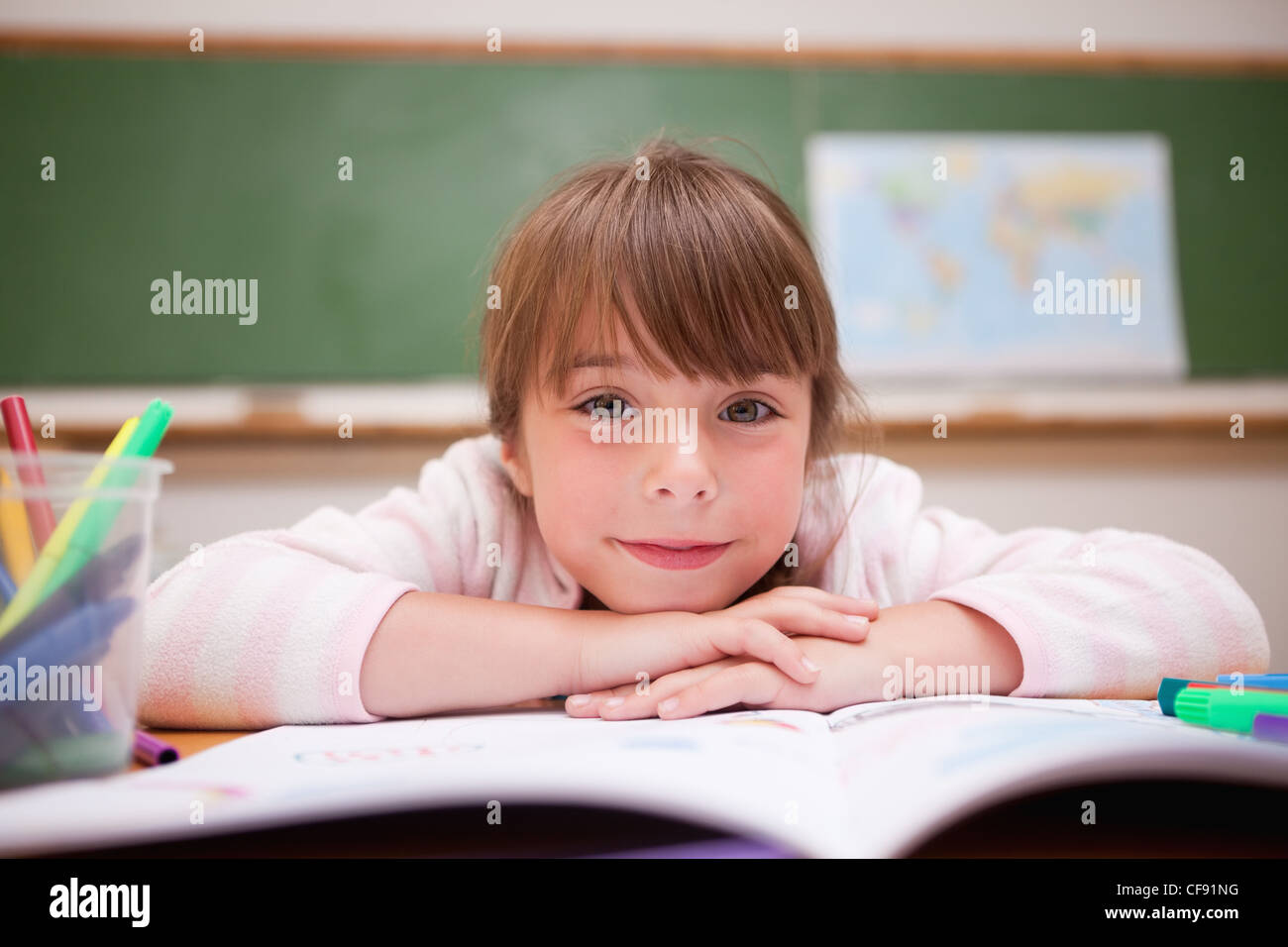 Smiling schoolgirl leaning on a desk Stock Photo - Alamy