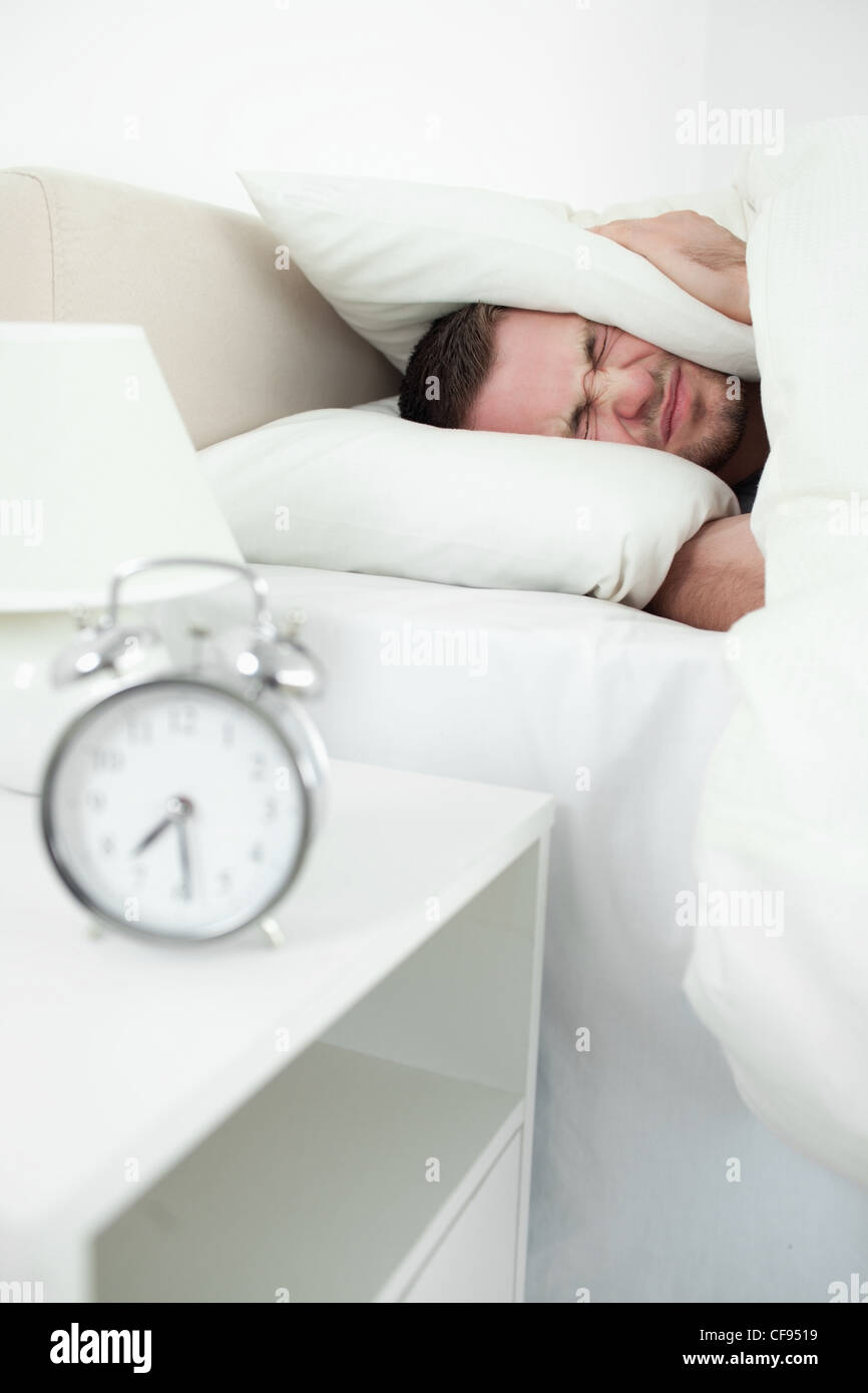 Portrait of a young man covering his ears with a pillow Stock Photo Alamy