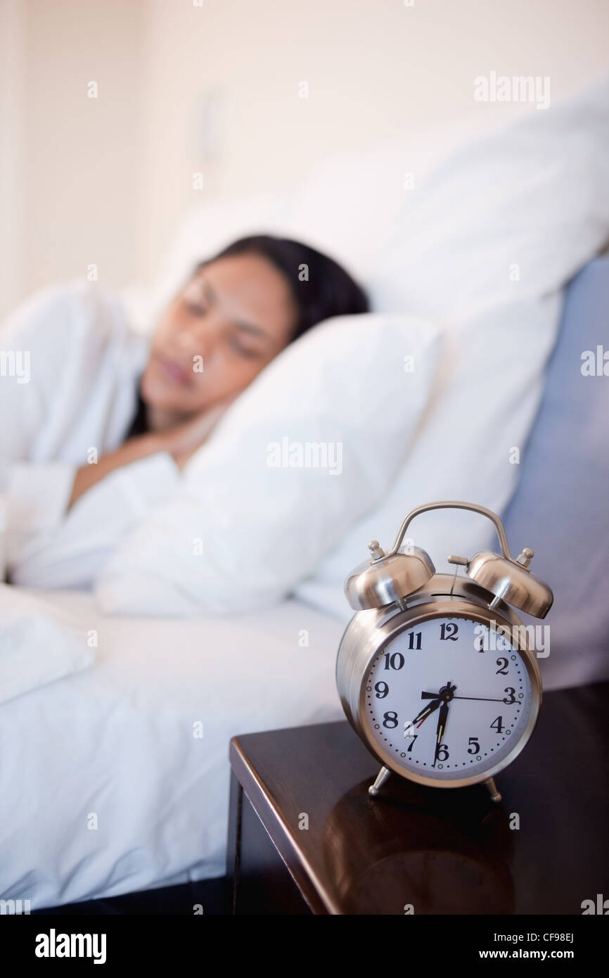Alarm clock next to bed in which woman is sleeping Stock Photo Alamy