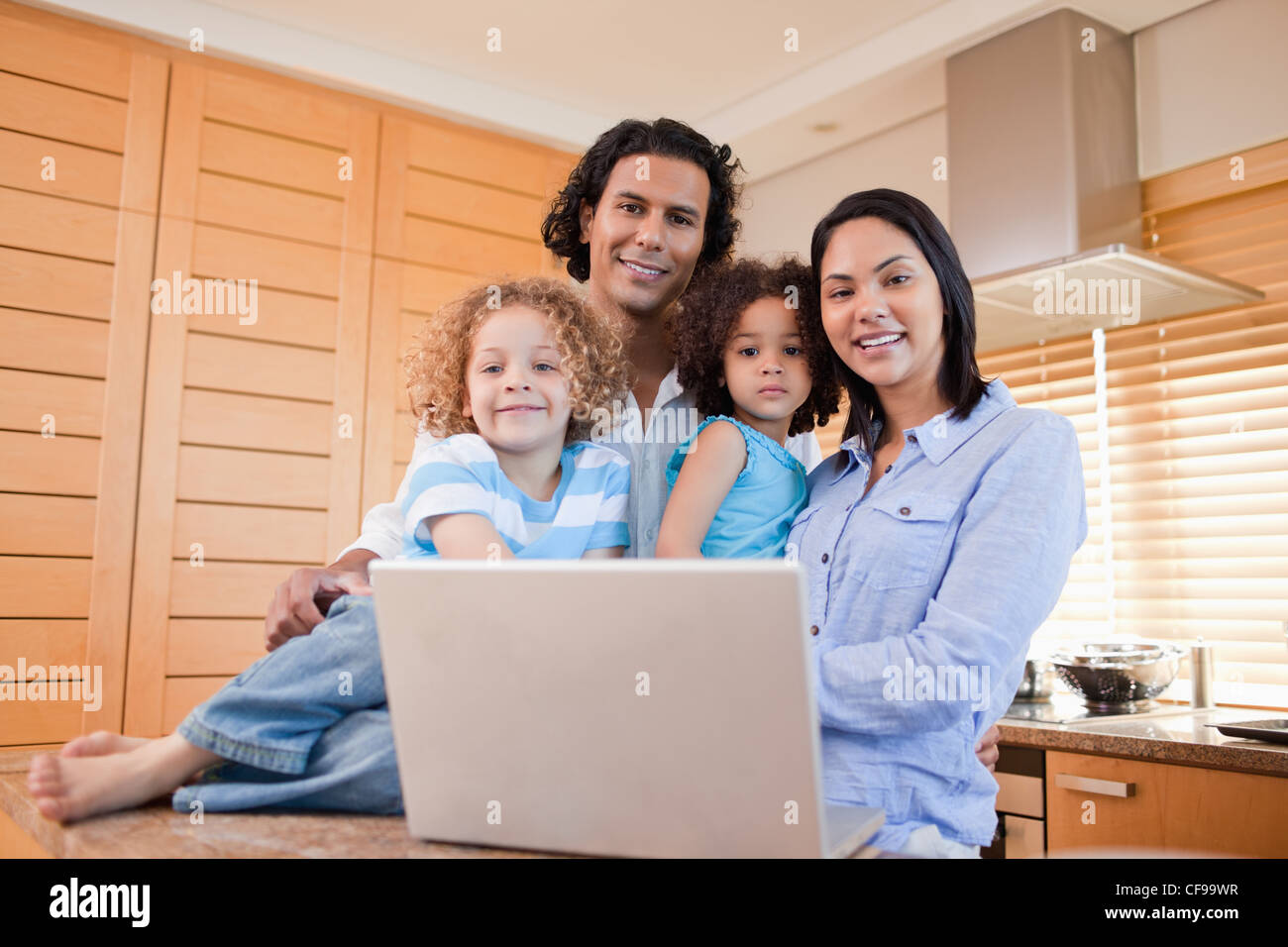 Happy family with laptop standing in the kitchen together Stock Photo ...