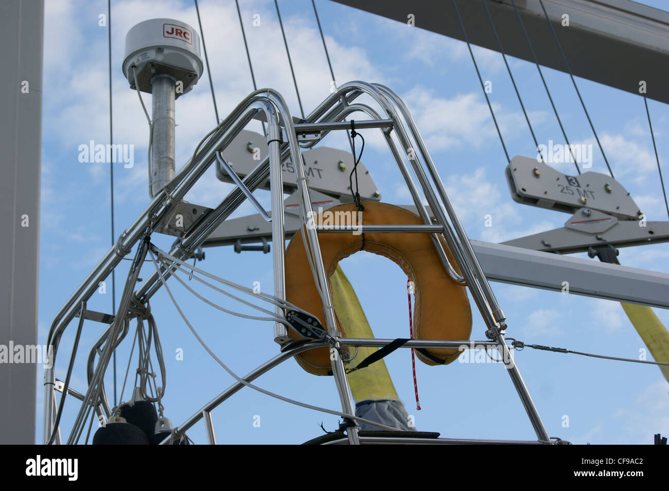 USCG approved type 5 yellow horseshoe buoy on a sailboat with rigging and radar in the background. Stock Photo