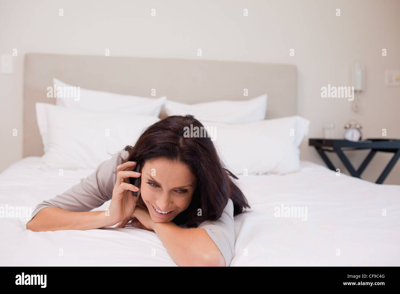 Woman having a joyful phone call on her bed Stock Photo