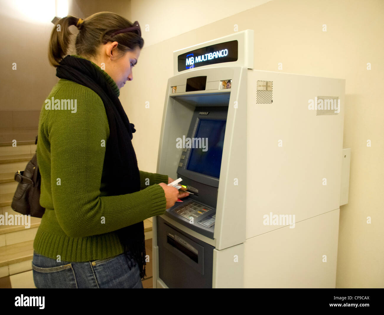 Young woman using ATM machine to withdraw cash Stock Photo