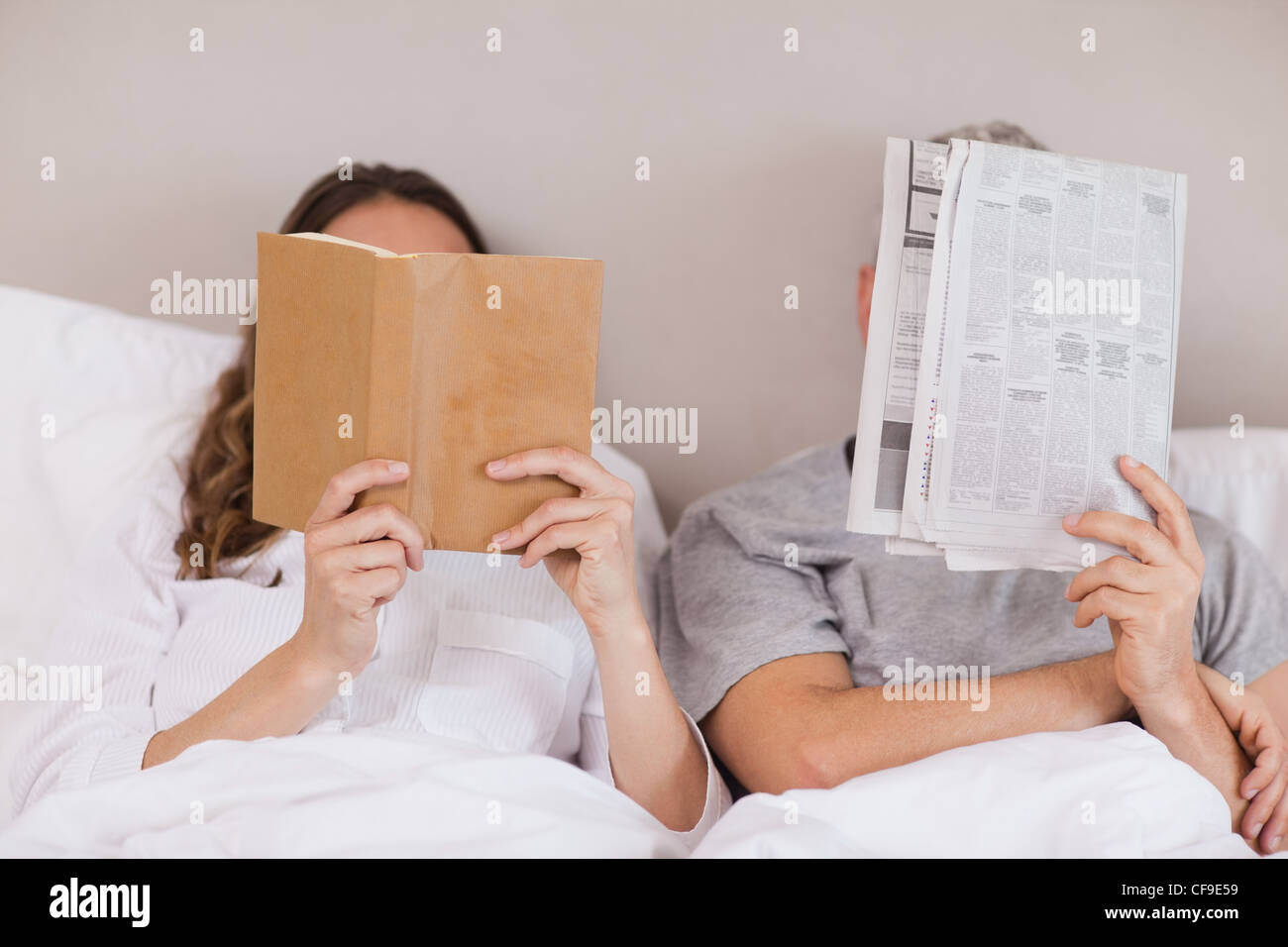 Woman reading a book while her companion is reading a newspaper Stock