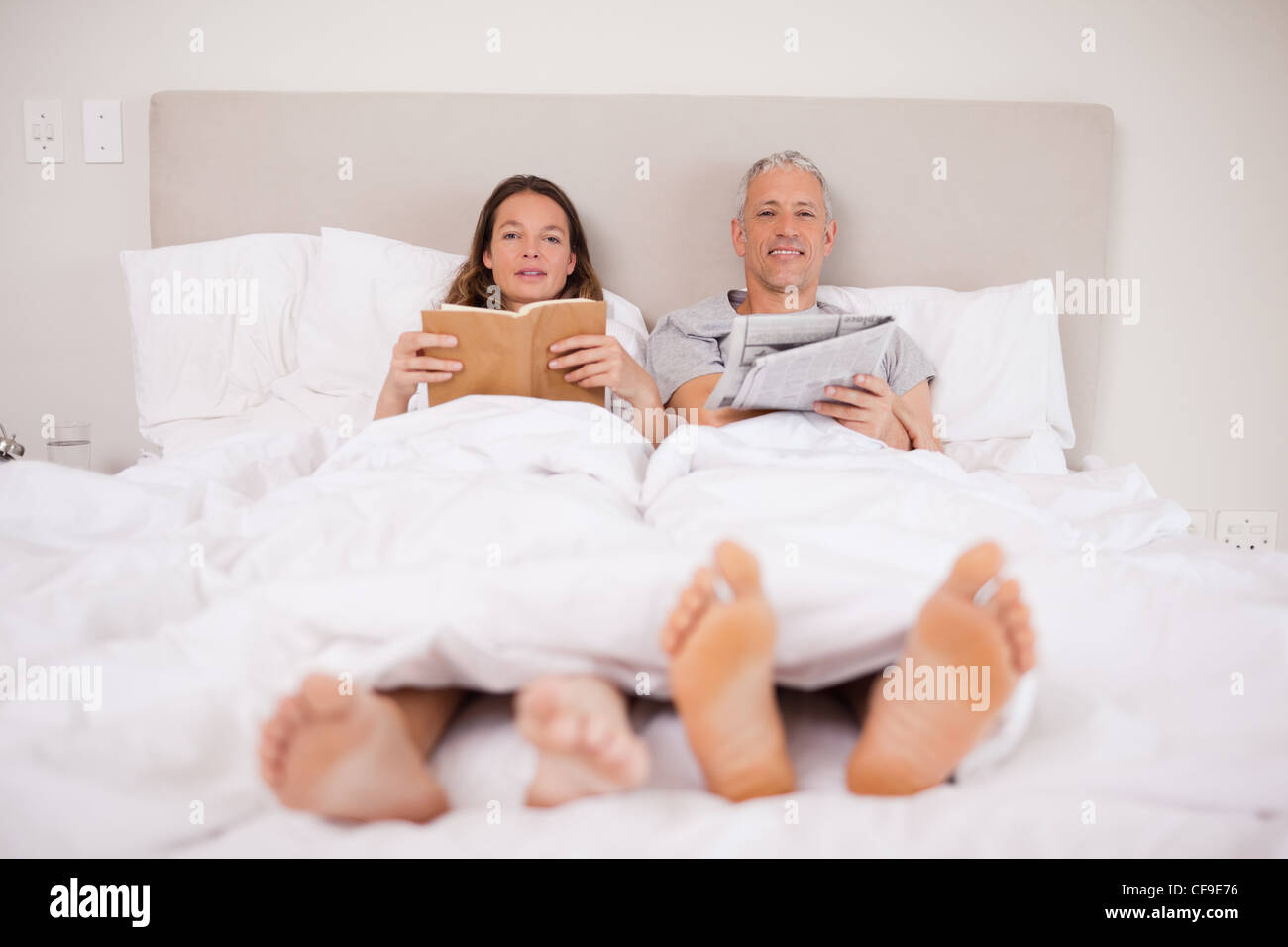 Man reading a newspaper while his wife is reading a book Stock Photo