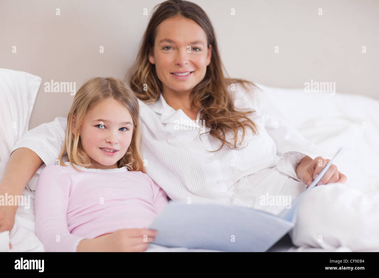 Smiling girl reading a book with her mother Stock Photo - Alamy