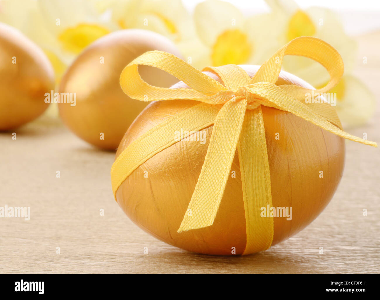 Easter eggs with bows on gold over floral background Stock Photo - Alamy