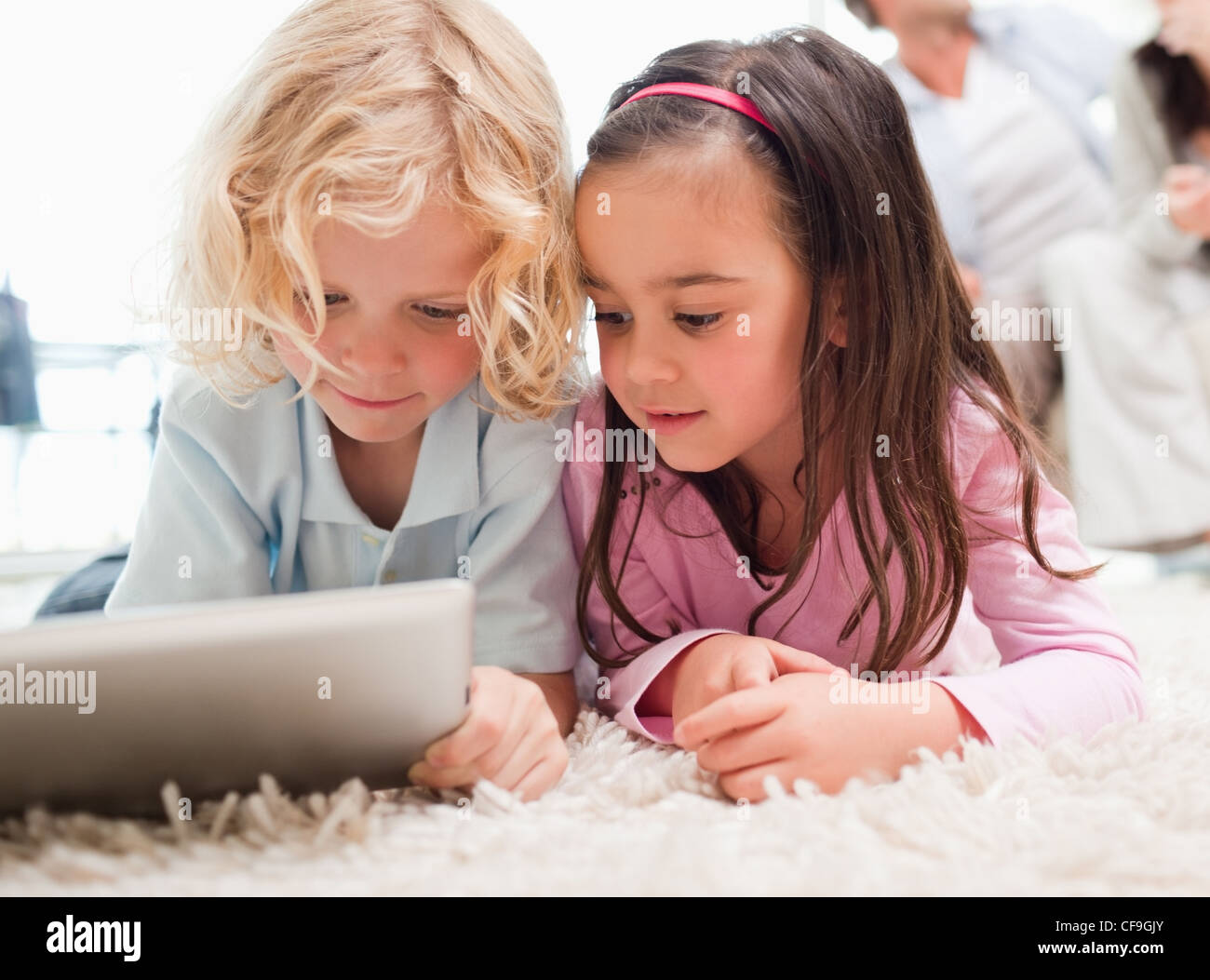 Children using a tablet computer while their parents are in the ...