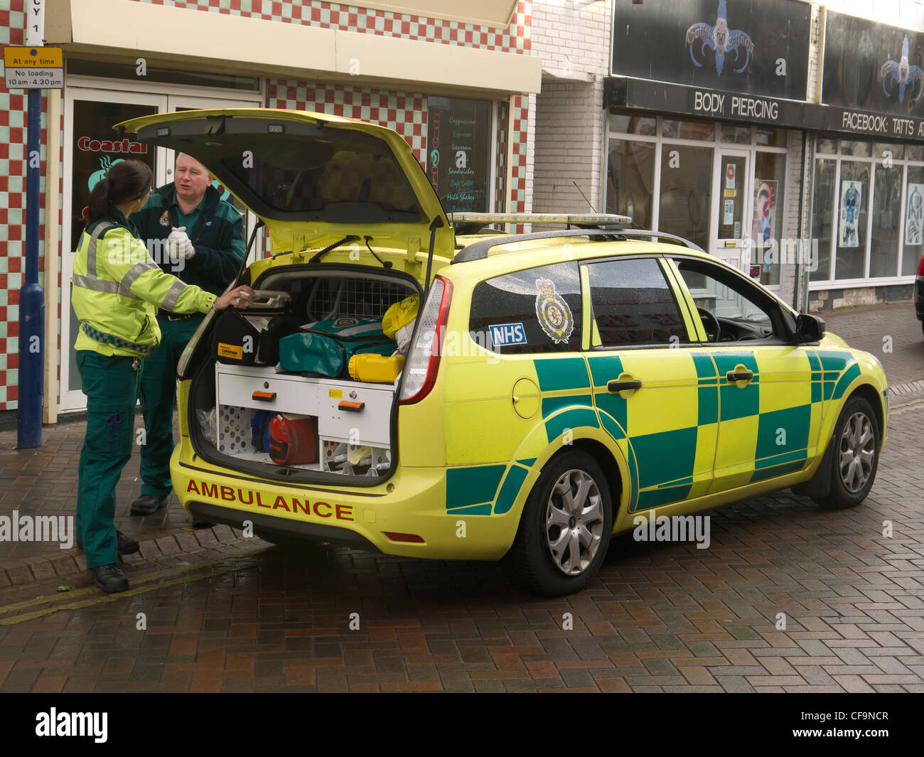 Two paramedics talking beside their estate car based ambulance Stock Photo