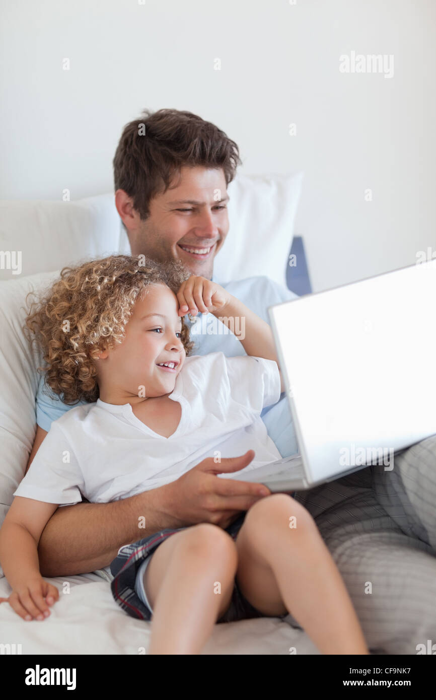 Smiling father and child on bed with laptop Stock Photo - Alamy
