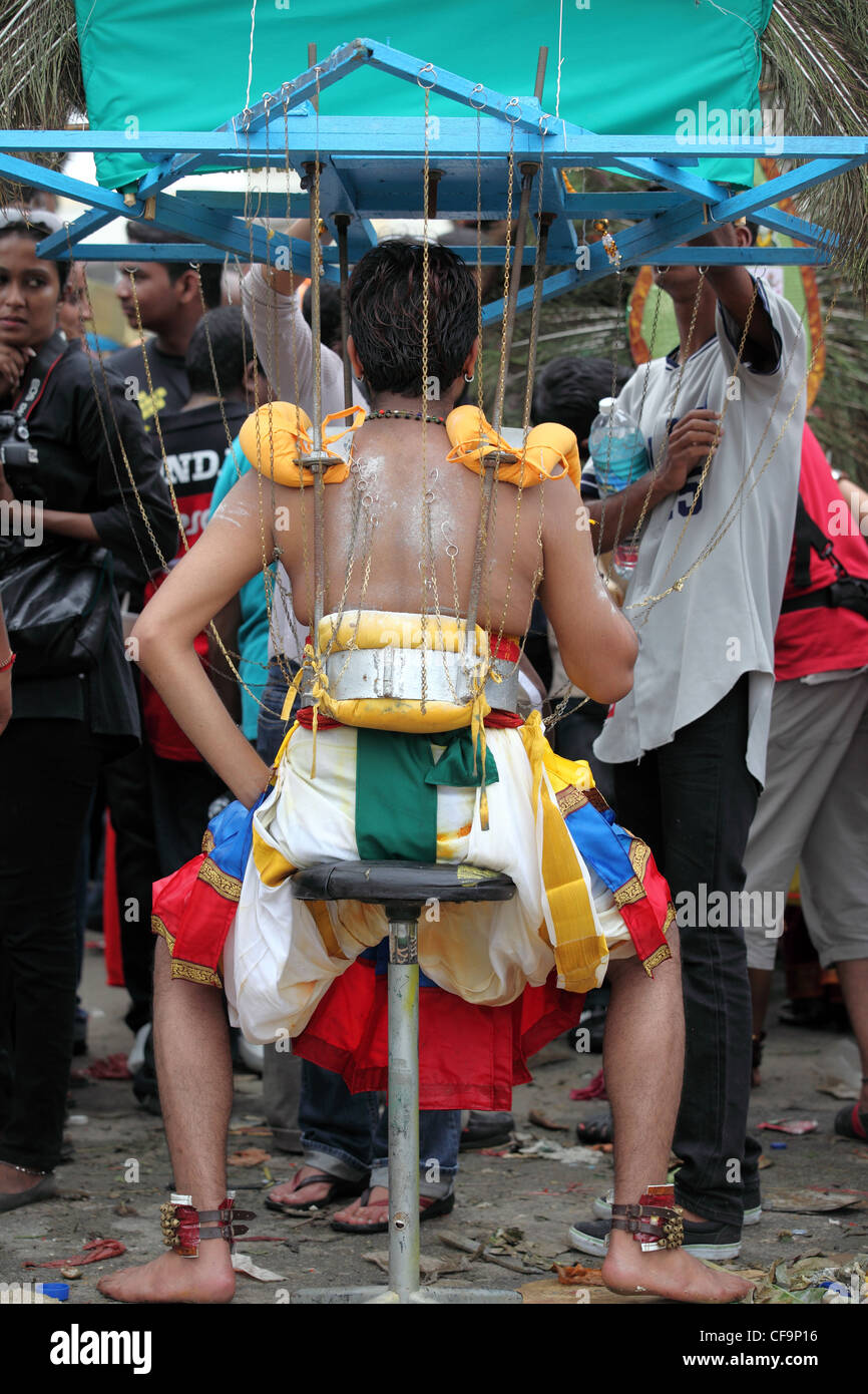 Devotee with kavadii takes a rest during Thaipusam Hindu festival at Batu Caves in Kuala Lumpur, Malaysia Stock Photo
