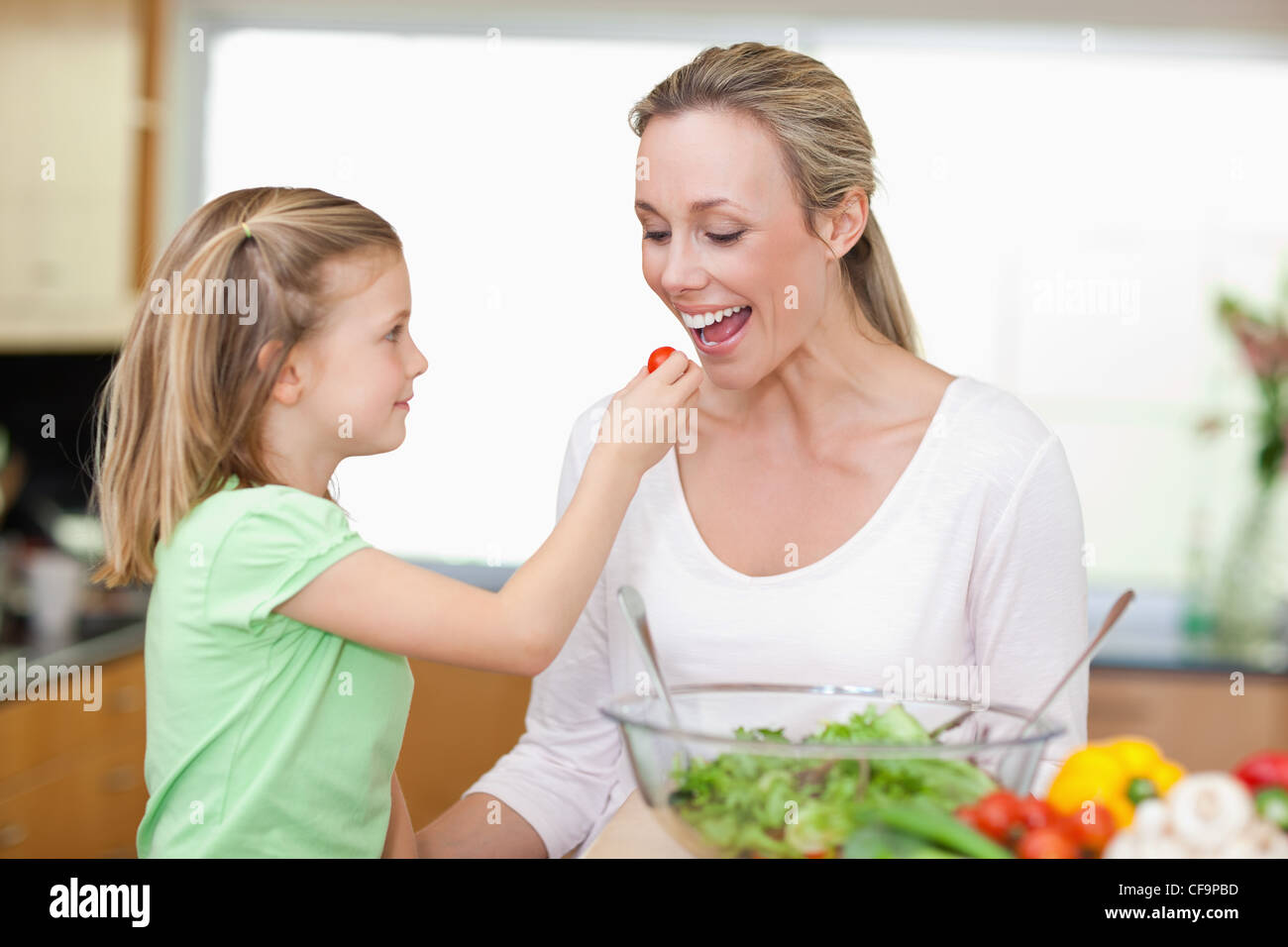 Girl feeding her mother with tomato Stock Photo Alamy