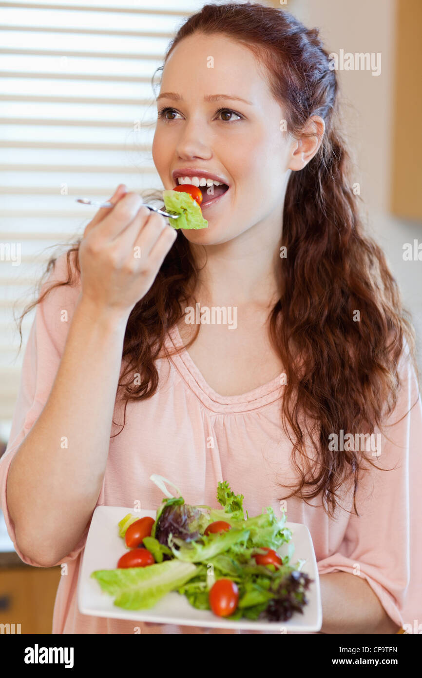 Woman eating salad in the kitchen Stock Photo Alamy