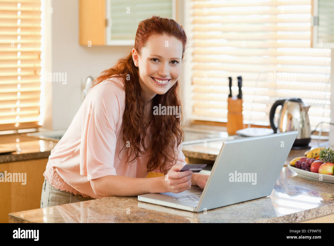 Woman booking flight online in the kitchen Stock Photo
