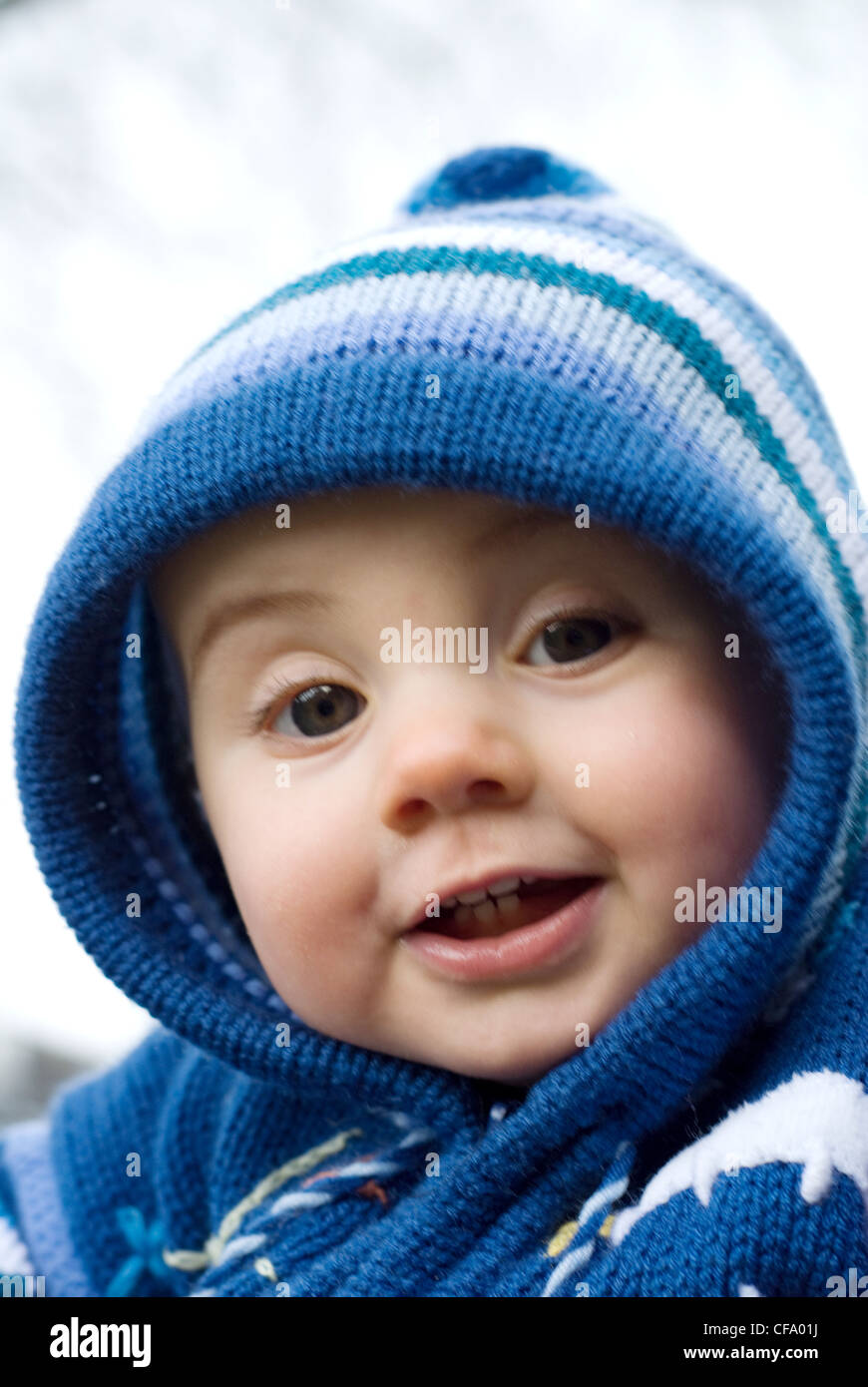 A female baby with fair hair, wearing a blue hooded cardigan, unsmiling, looking at camera Joel Penn Stock Photo