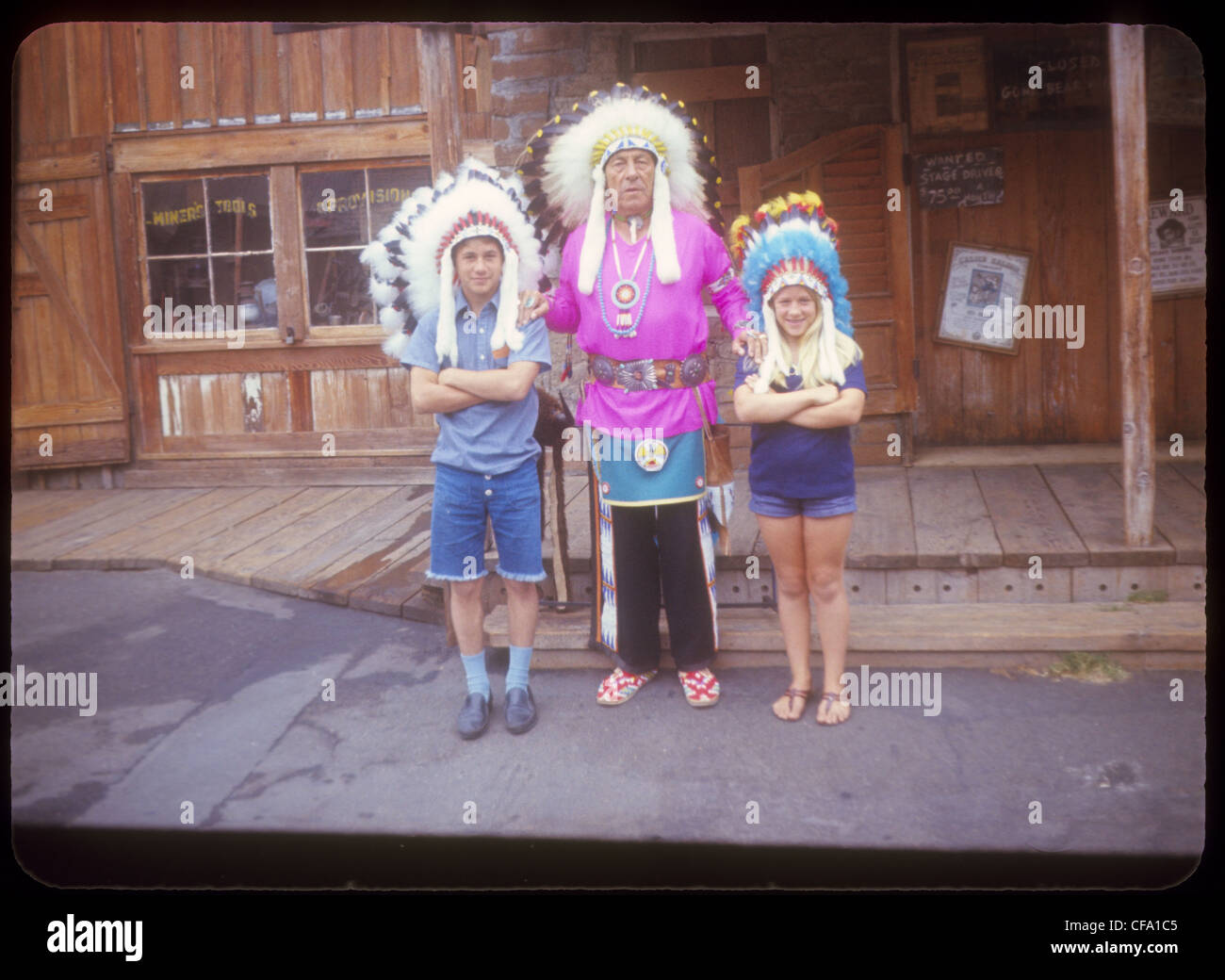 Two children posing for photo with a man dressed as an american Indian not politcally correct stereotype native Stock Photo