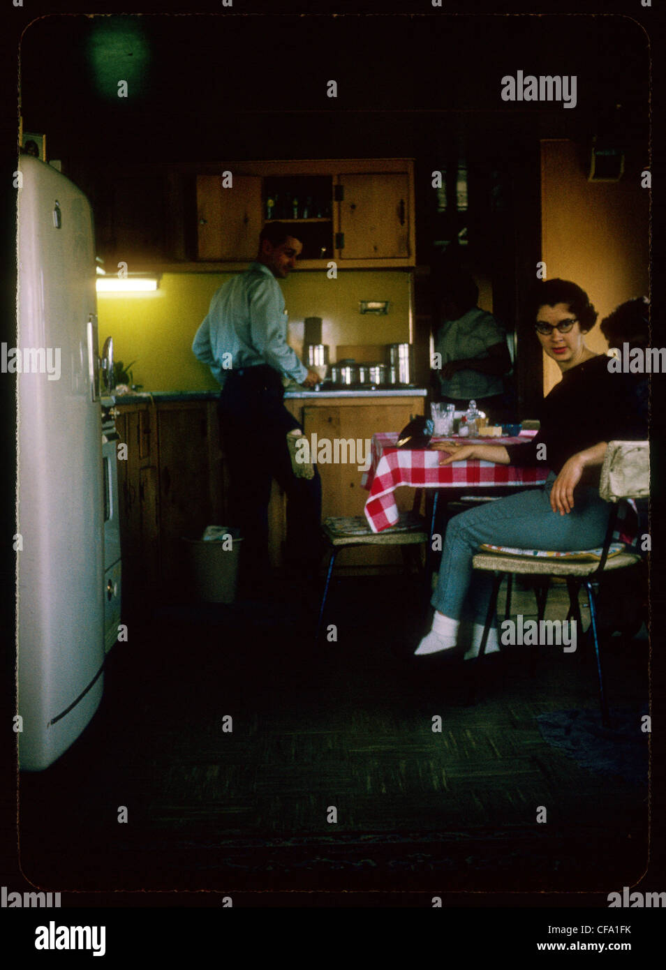 woman sitting man standing in kitchen during the 1960s Stock Photo