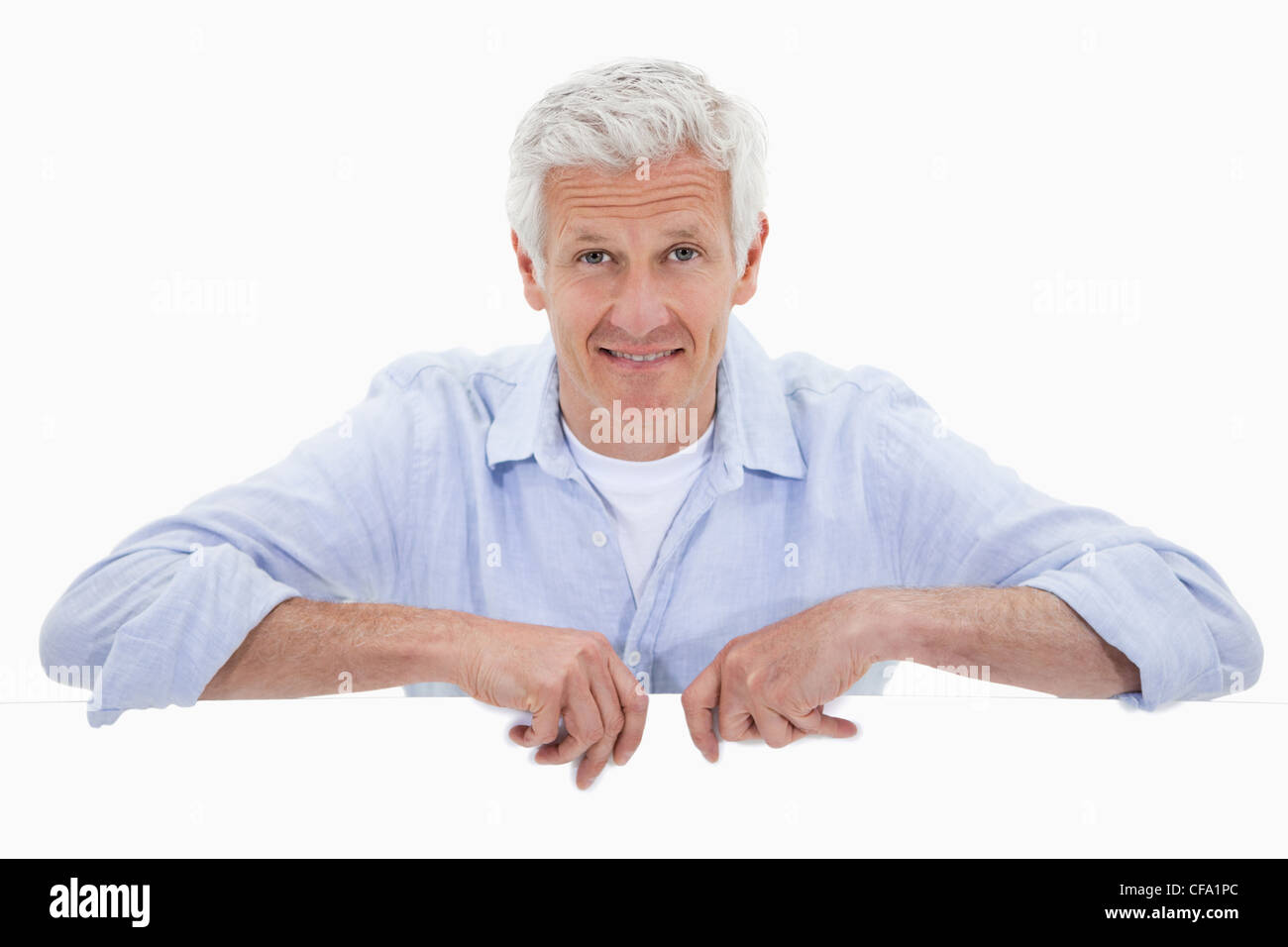 Portrait of a smiling mature man standing behind blank panel Stock Photo