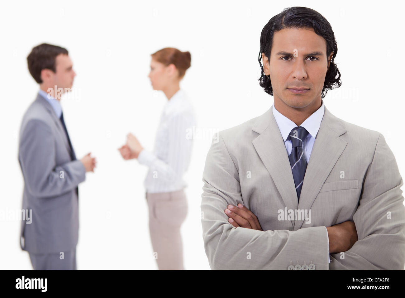 Serious businessman with talking colleagues behind him Stock Photo - Alamy