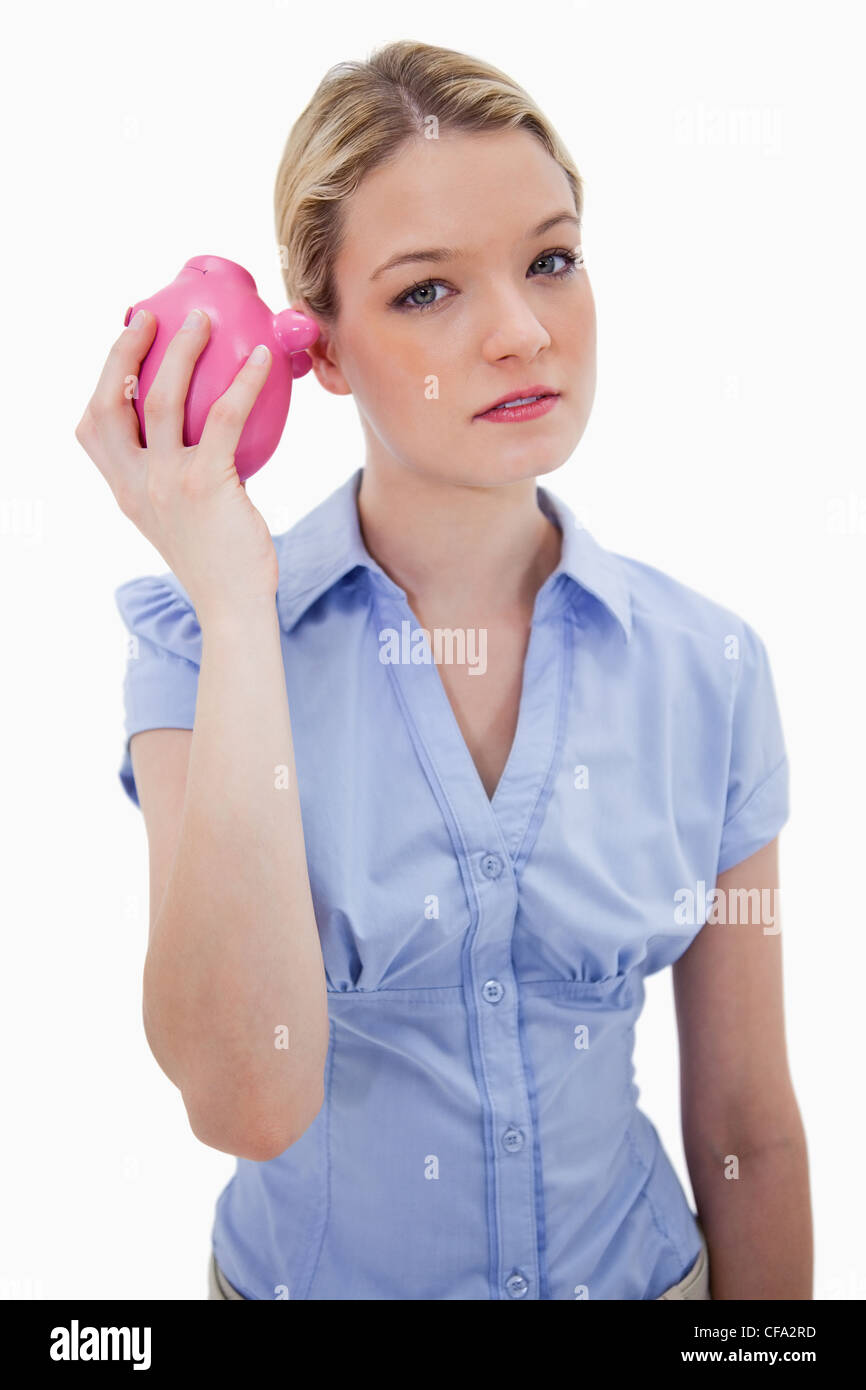 Woman curiously shaking her piggy bank Stock Photo