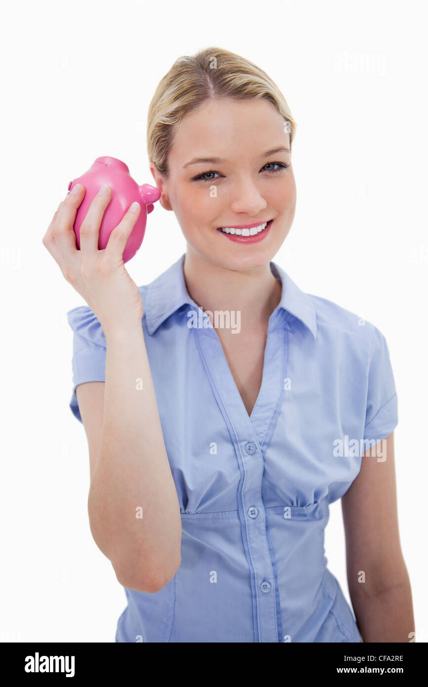 Smiling woman shaking her piggy bank Stock Photo